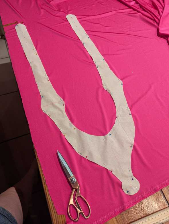 A photo of the calico cutout pinned atop the spandex fabric. Scissors are lying on top of the material.